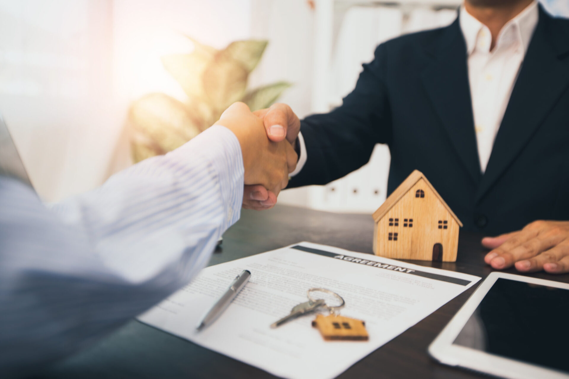 successful negotiate and handshake of buying and selling or real estate concept, home agent shake hand with customer after sign contract and finishes deal purchase house success